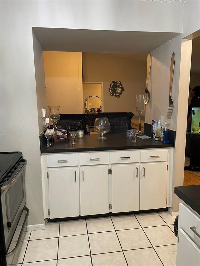 kitchen with white cabinets, light tile patterned floors, and range with electric stovetop