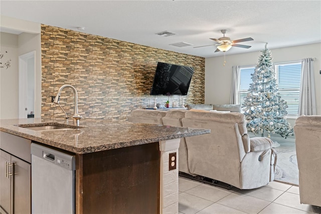 kitchen featuring ceiling fan, dishwasher, sink, an island with sink, and light tile patterned floors