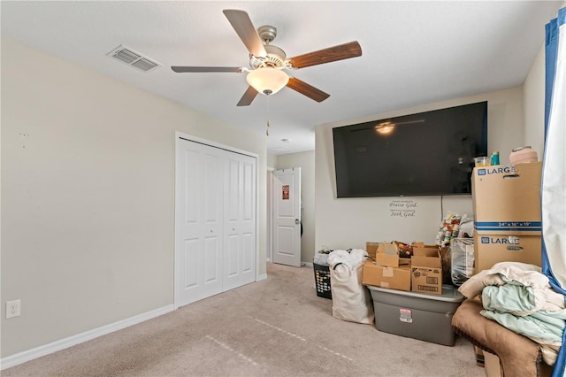 interior space featuring ceiling fan, light carpet, and a closet