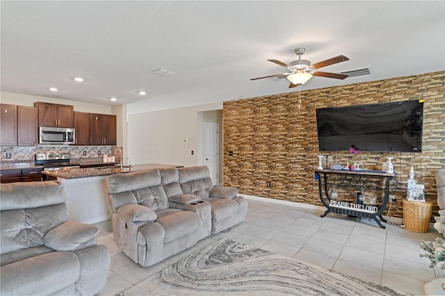 tiled living room featuring ceiling fan and sink