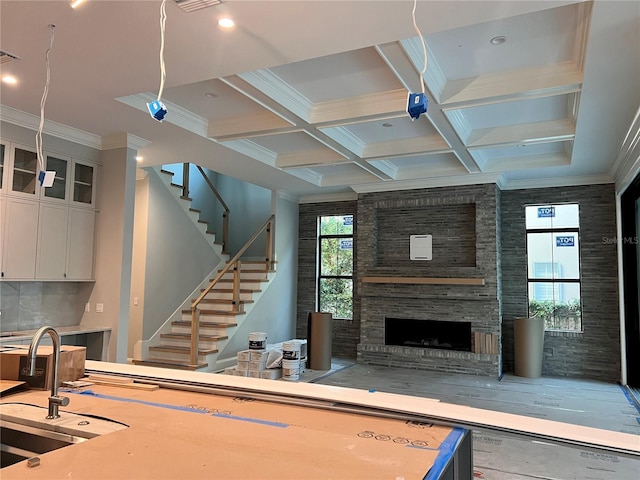 living area with a large fireplace, crown molding, stairs, beam ceiling, and coffered ceiling