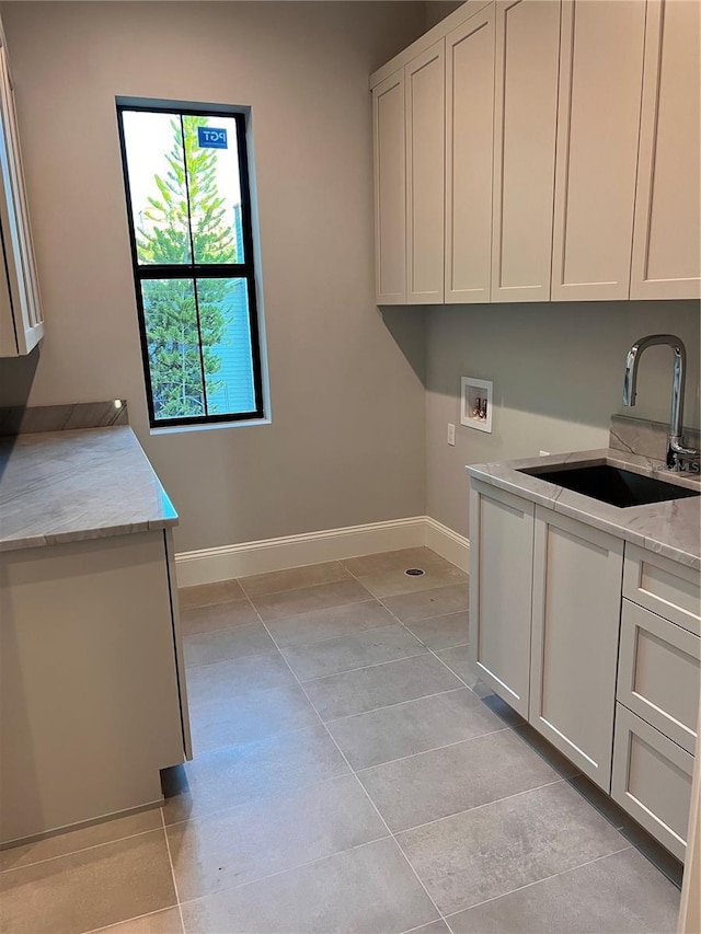 clothes washing area featuring light tile patterned flooring, a sink, baseboards, cabinet space, and hookup for a washing machine