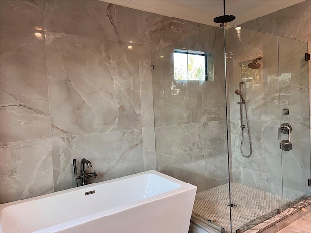 full bath featuring a shower stall, a freestanding tub, and tile walls
