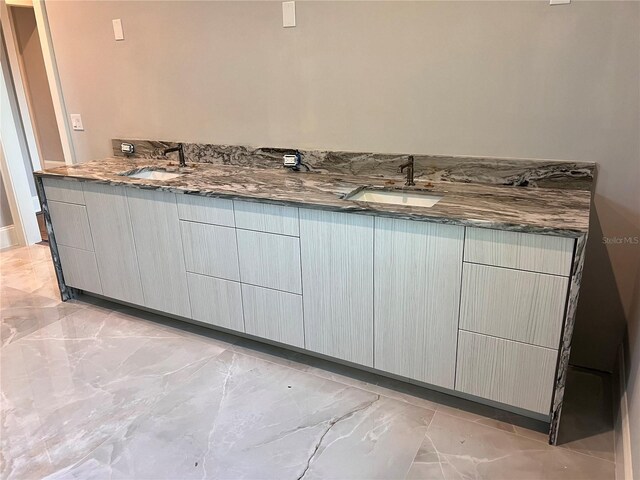 bathroom featuring marble finish floor, a sink, and double vanity