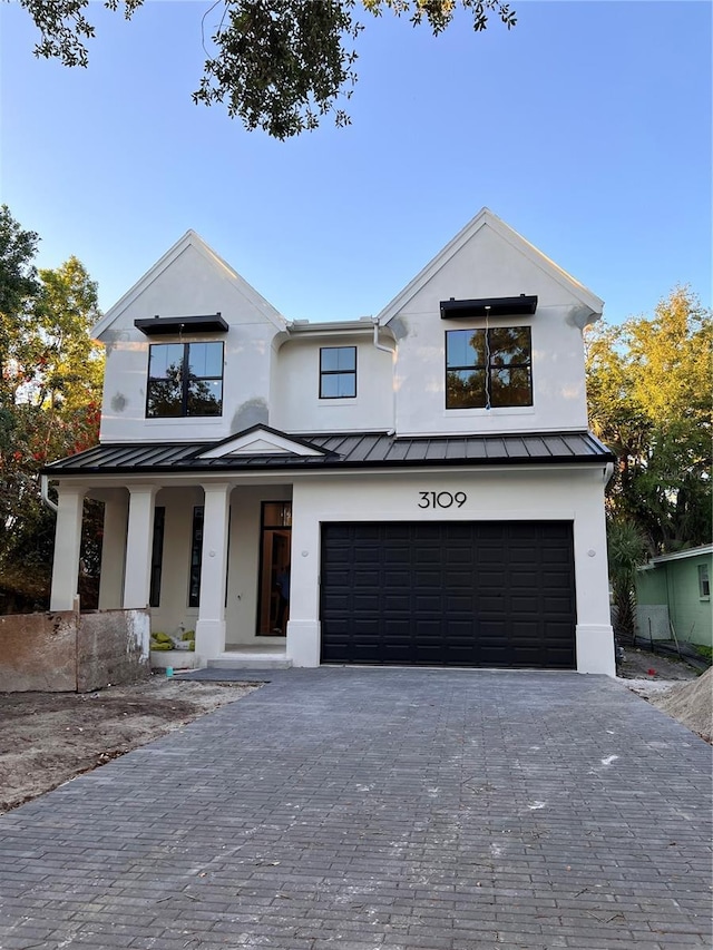 modern farmhouse featuring metal roof, a standing seam roof, and decorative driveway