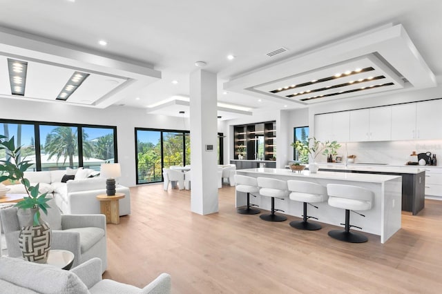 kitchen featuring white cabinets, a center island with sink, a breakfast bar area, and light hardwood / wood-style flooring