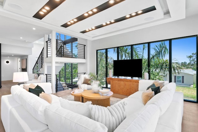 living room featuring a tray ceiling, a high ceiling, and light hardwood / wood-style flooring