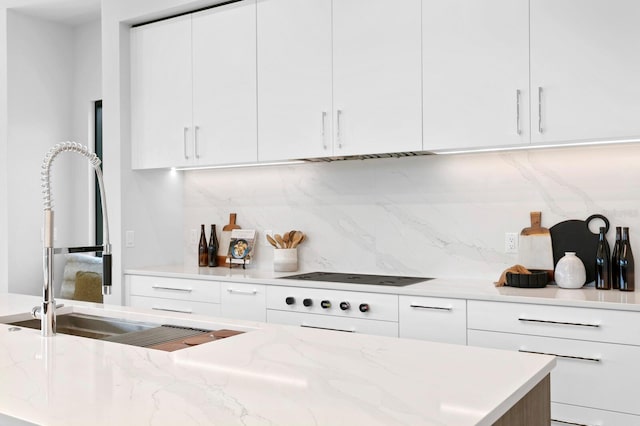 kitchen featuring decorative backsplash, white cabinetry, and light stone counters