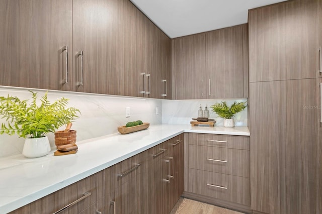 kitchen featuring decorative backsplash, light hardwood / wood-style floors, and light stone countertops