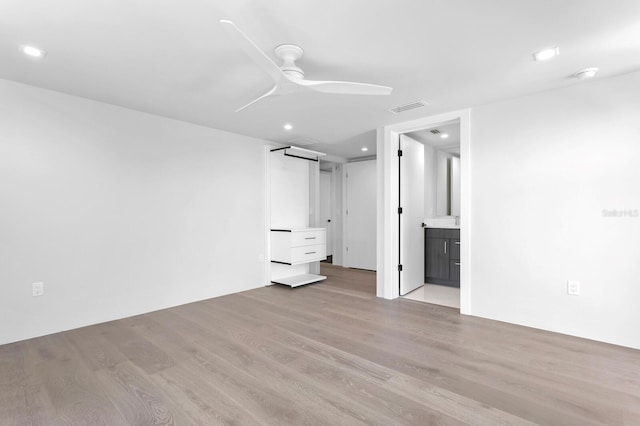 unfurnished bedroom with ceiling fan, connected bathroom, and light hardwood / wood-style flooring