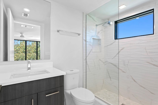 bathroom with vanity, ceiling fan, toilet, and a tile shower