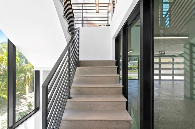 stairway with plenty of natural light, floor to ceiling windows, and a high ceiling