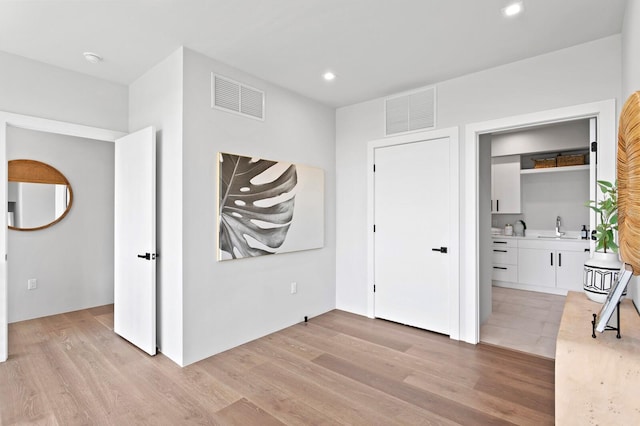 unfurnished bedroom with light wood-type flooring, ensuite bath, and sink