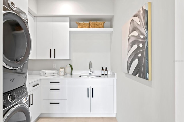 clothes washing area with cabinets, sink, and stacked washer and clothes dryer