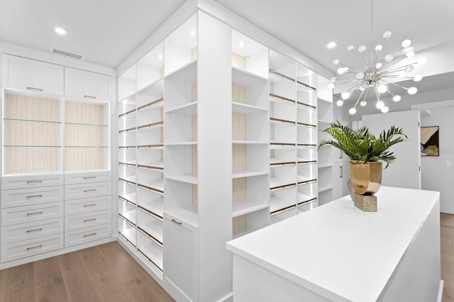 walk in closet featuring hardwood / wood-style flooring and a chandelier