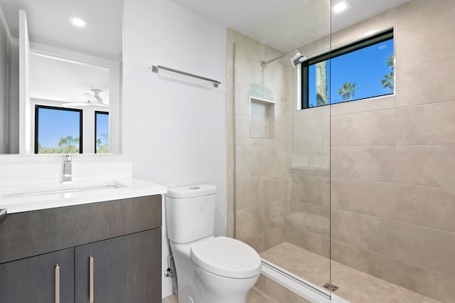 bathroom featuring tiled shower, plenty of natural light, vanity, and toilet