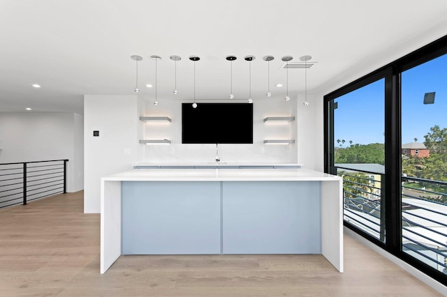 kitchen featuring floor to ceiling windows, decorative light fixtures, and light wood-type flooring