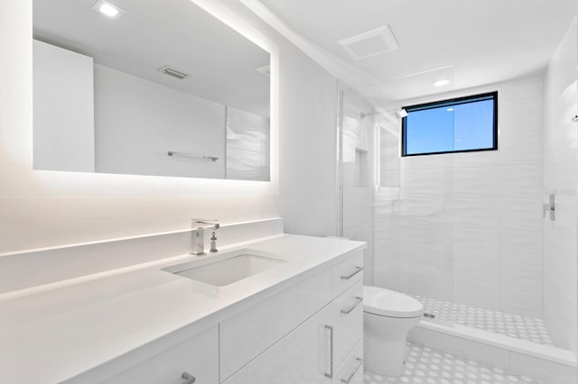 bathroom with tiled shower, vanity, and toilet