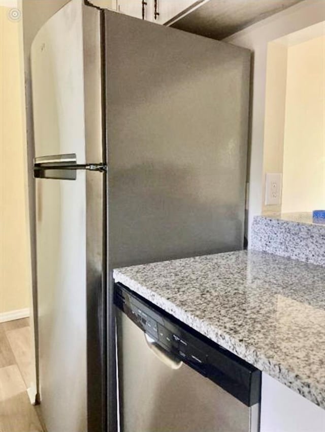 kitchen with appliances with stainless steel finishes, light wood-type flooring, and light stone countertops