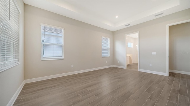 interior space featuring connected bathroom, dark wood-type flooring, and a raised ceiling