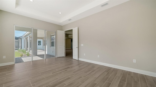 empty room with dark hardwood / wood-style flooring and a tray ceiling