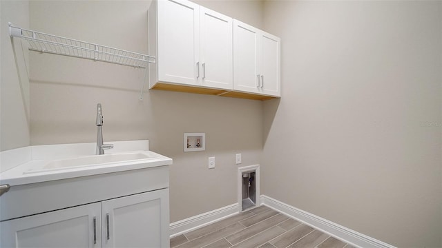 washroom with hookup for an electric dryer, hookup for a washing machine, cabinets, light hardwood / wood-style floors, and sink