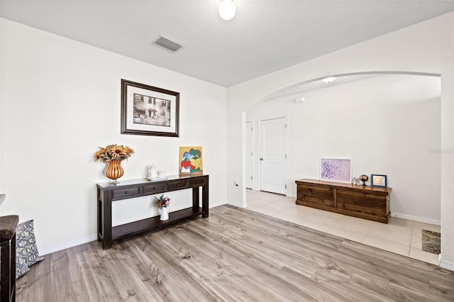 corridor with light hardwood / wood-style floors and a textured ceiling