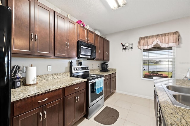 kitchen with black appliances, light stone counters, light tile patterned floors, and sink