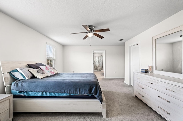 carpeted bedroom featuring a textured ceiling, ceiling fan, and ensuite bathroom