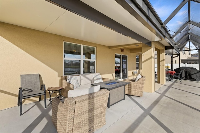 view of patio featuring glass enclosure and an outdoor living space with a fire pit