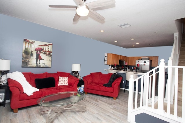 living room featuring ceiling fan and light hardwood / wood-style floors