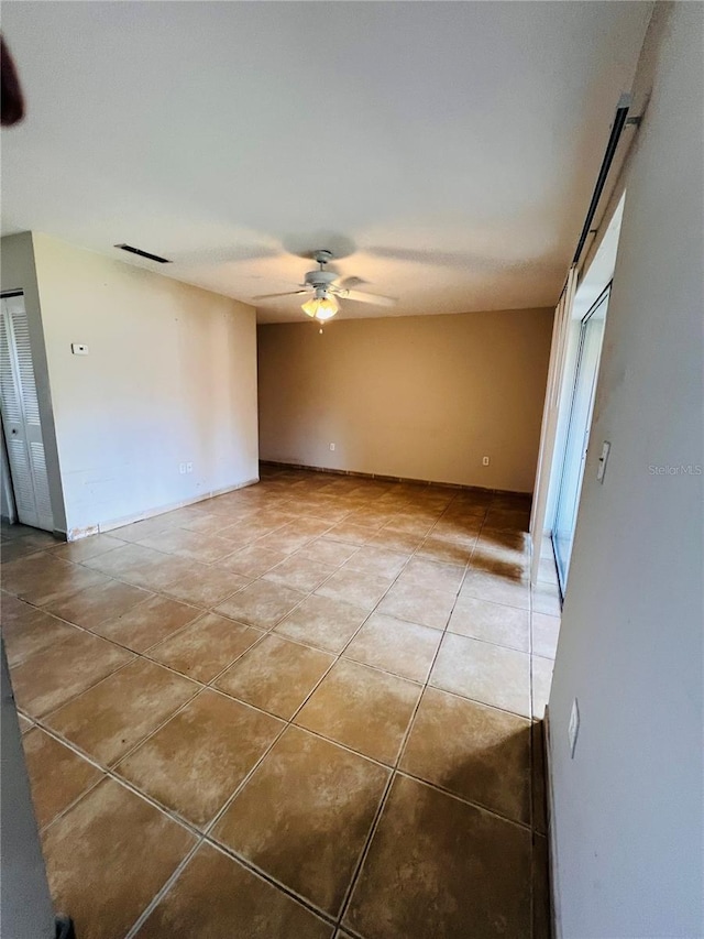 tiled empty room featuring ceiling fan