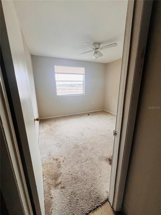 carpeted spare room featuring ceiling fan