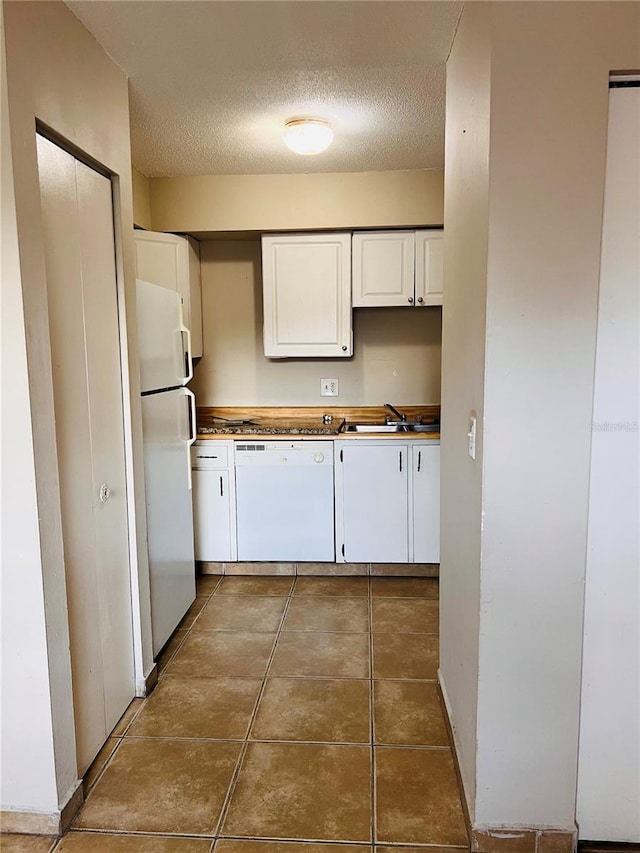 kitchen with tile patterned floors, white appliances, white cabinetry, sink, and a textured ceiling