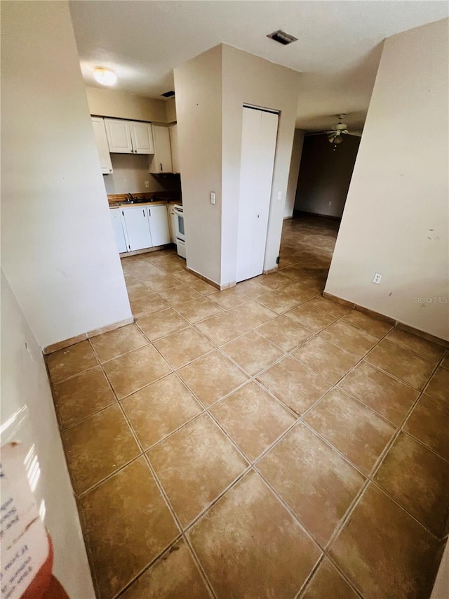 kitchen with ceiling fan, light tile patterned floors, electric stove, and white cabinetry