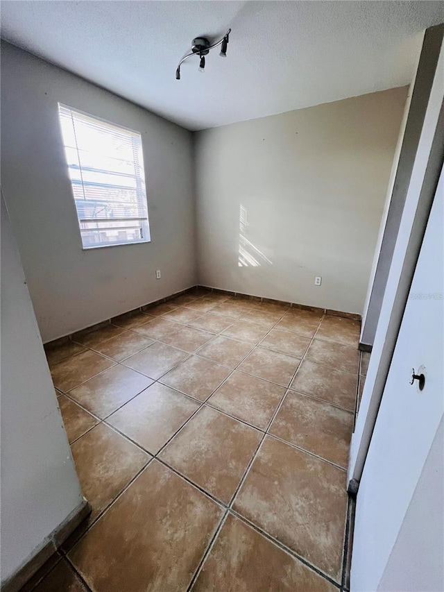 tiled empty room featuring a textured ceiling