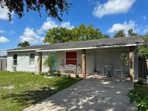 ranch-style home featuring stucco siding, a front yard, fence, a garage, and driveway