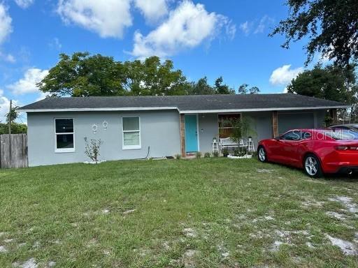 ranch-style house with stucco siding, an attached garage, fence, and a front yard