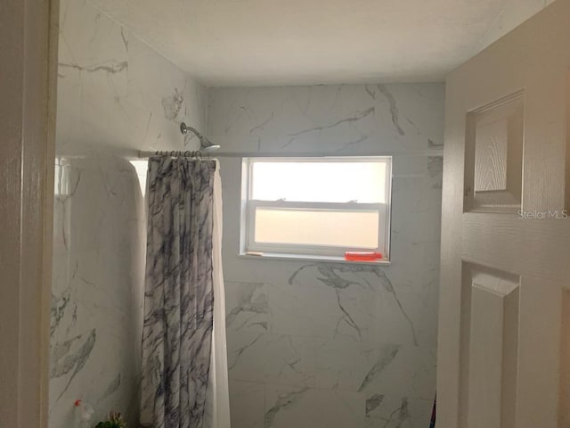 bathroom featuring a marble finish shower