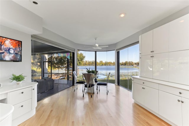 dining room featuring a water view, ceiling fan, and light hardwood / wood-style floors