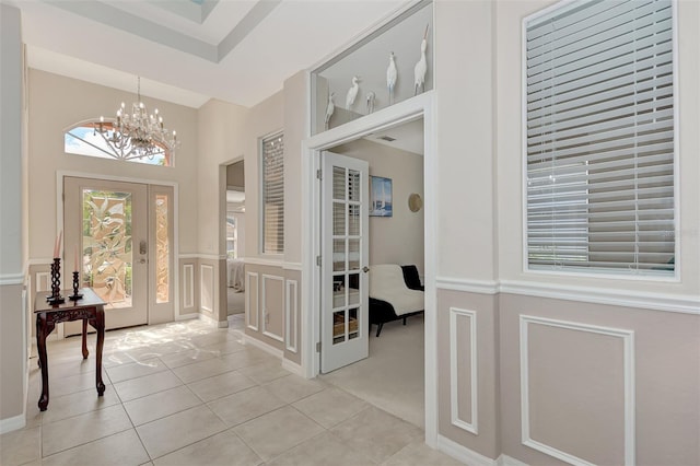 tiled foyer with a notable chandelier and french doors