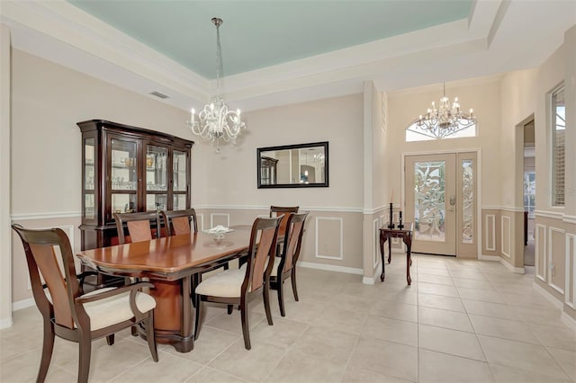 dining space with a tray ceiling, light tile floors, french doors, and an inviting chandelier