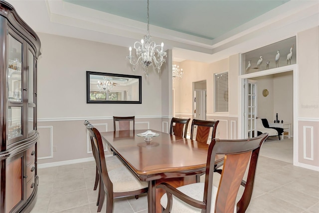 tiled dining room featuring a tray ceiling and a chandelier