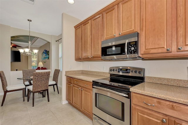 kitchen with an inviting chandelier, light tile flooring, appliances with stainless steel finishes, and light stone counters