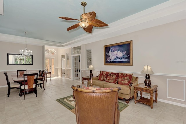 living room with a raised ceiling, french doors, ceiling fan with notable chandelier, and light tile flooring