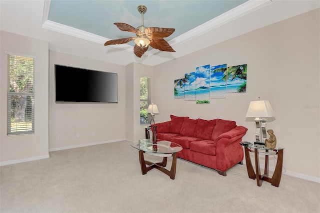 carpeted living room with crown molding, a tray ceiling, and ceiling fan