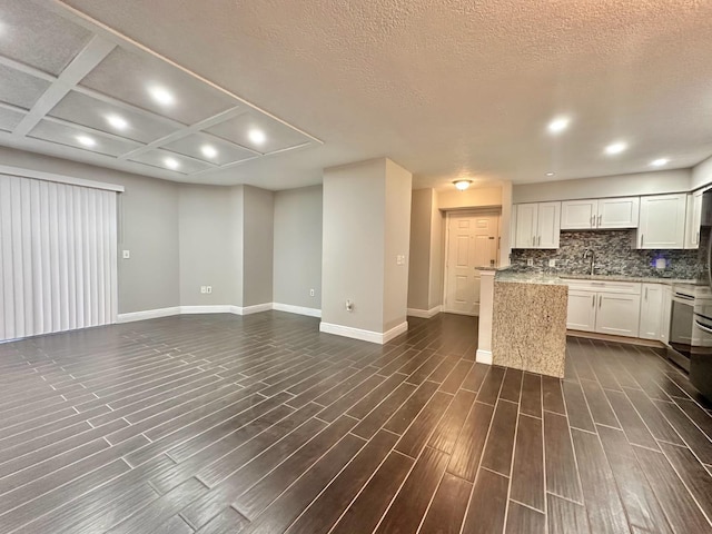 kitchen featuring white cabinetry, dark wood-type flooring, light stone counters, and decorative backsplash