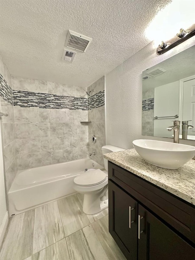 full bathroom featuring vanity, tiled shower / bath, a textured ceiling, and toilet