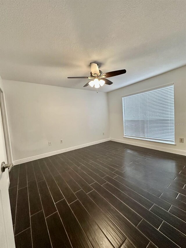 spare room featuring a textured ceiling, dark wood-type flooring, and ceiling fan