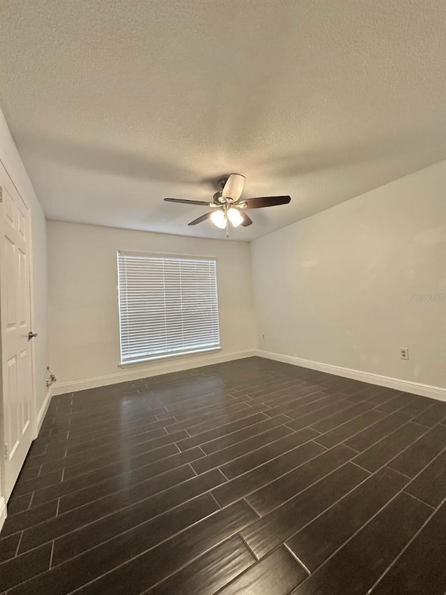 spare room with dark wood-type flooring, a textured ceiling, and ceiling fan